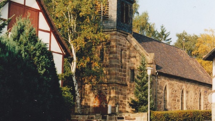 Kirche mit hohem Kirchturm und Kreuz an der Spitze.