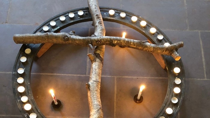 Umweltfreundlicher Kerzenhalter mit Birkenzweigen, die eine runde Basis umschließen und mehrere brennende Kerzen halten.