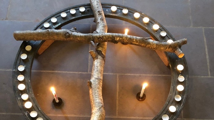 Umweltfreundlicher Kerzenhalter mit Birkenzweigen, die eine runde Basis umschließen und mehrere brennende Kerzen halten.