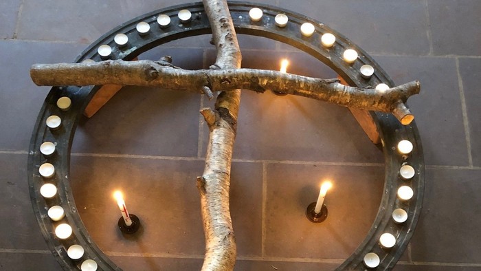 Umweltfreundlicher Kerzenhalter mit Birkenzweigen, die eine runde Basis umschließen und mehrere brennende Kerzen halten.