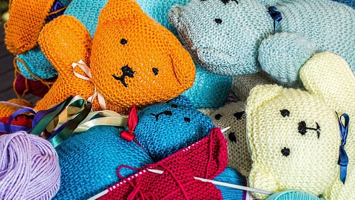 Bunte gestrickte Teddybären mit Wolle und Stricknadeln