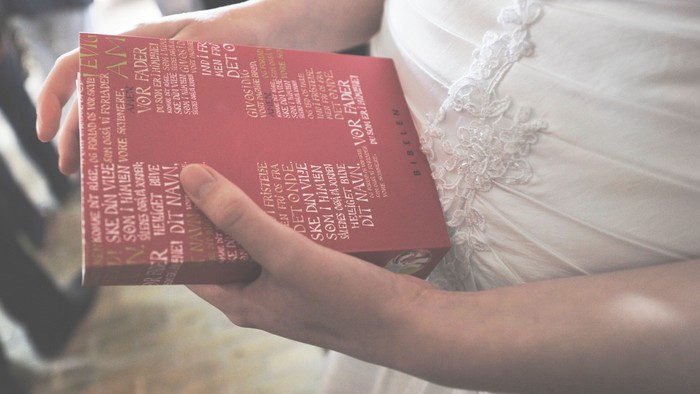 Unge hænder, der holder om en Bibel