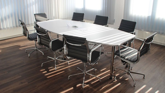 Ein moderner Konferenzraum mit einem großen Tisch und acht schwarzen Stühlen.