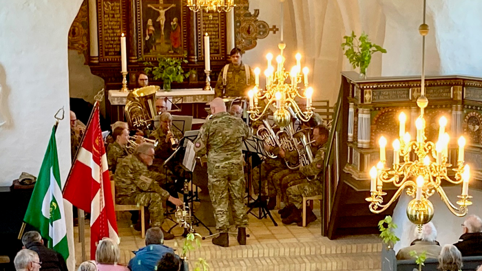 En højtidelig kirkelig ceremoni hædrer soldater med flag og militær tilstedeværelse under en gudstjeneste.