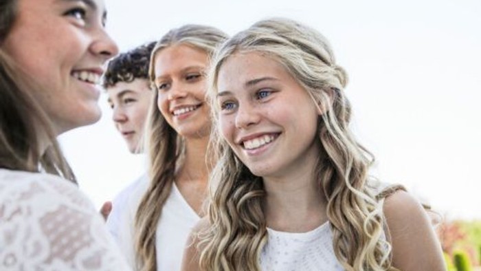 En gruppe unge piger smiler og ser glade ud.