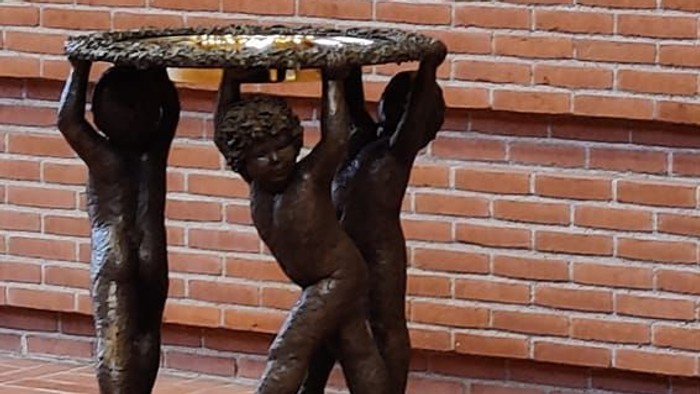 Bronzefigur af to børn, der bærer en plate på et murstenvægge