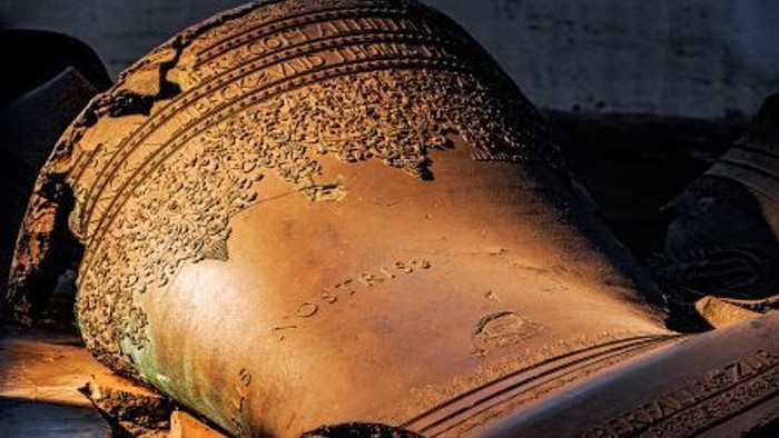 Ein antiker, verzierter Metalltopf liegt auf einer Holzoberfläche