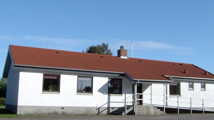 En hvid hytte med rødt tag og en trappe til indgangen.