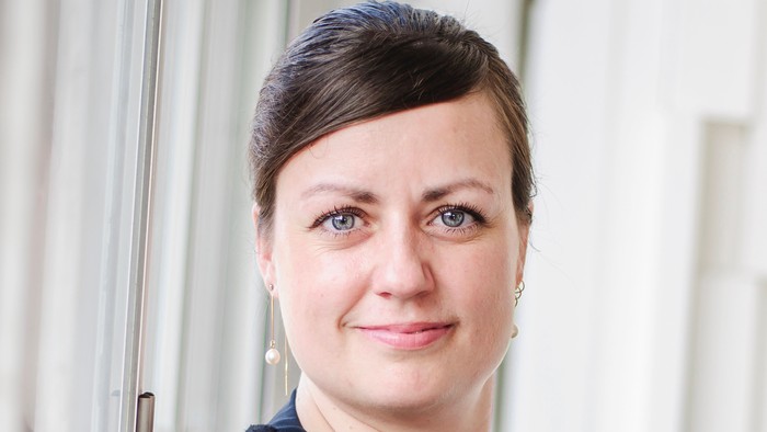 En kvinde med kort hår, der har en sort top på.