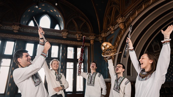  5 musikere med blæseinstrumenter og armene i vejret