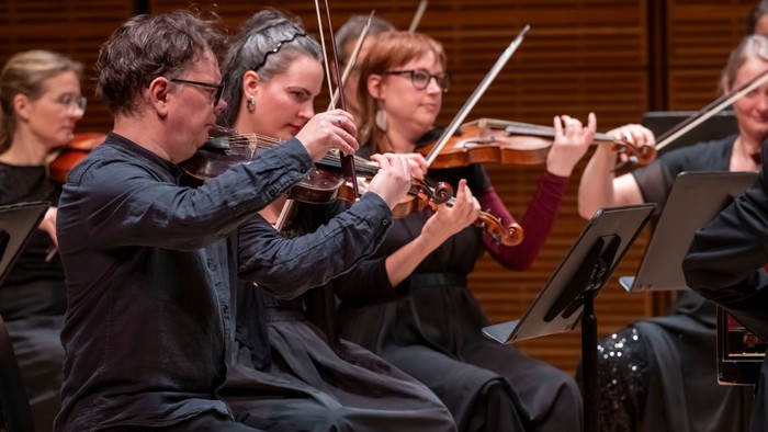 Strygekvartetmusikere, der spiller koncentreret på violiner under en koncertoptræden.