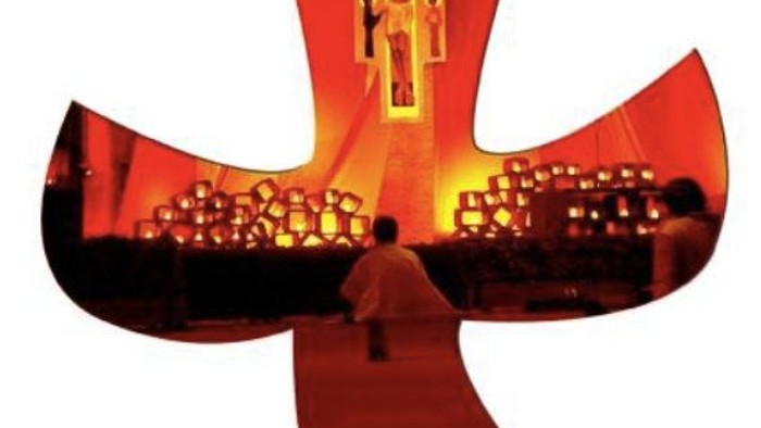 Ein Priester kniet vor einem großen Kreuz in einer Kirche.