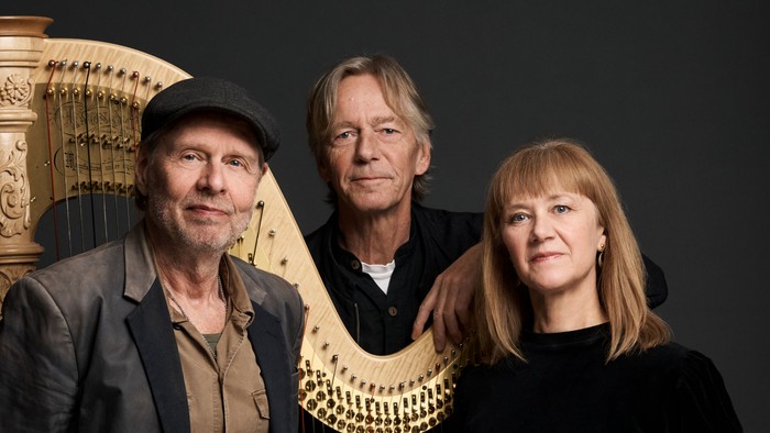 Musikere, der poser med en stor harpe mellem sig, og virker afslappede og fokuserede.