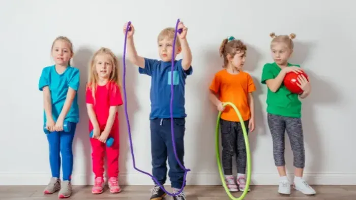 Fünf Kinder mit Sportequipment, die drinnen posieren.