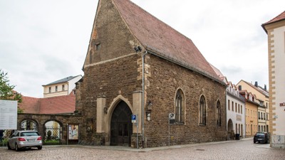 Altes Steingebäude mit spitzem Dach in Kopfsteinpflasterstraße