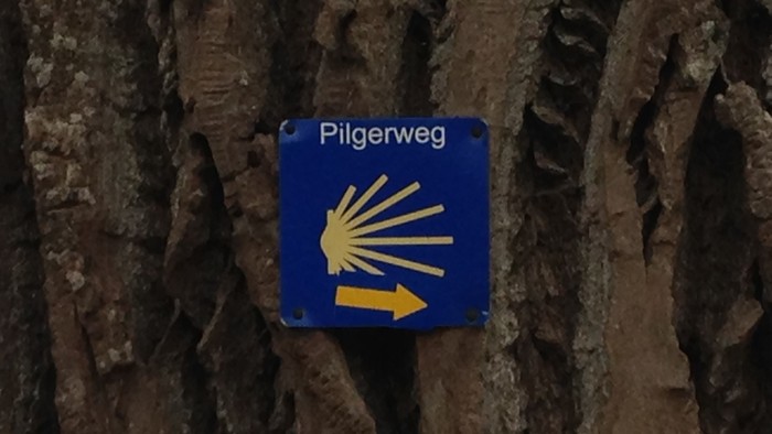 Blaues Pilgerweg-Schild an einer Felswand