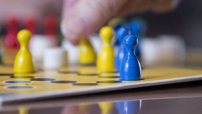 Eine Person spielt ein Brettspiel mit bunten Figuren.