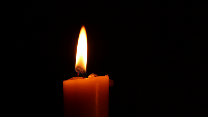 Single lit candle in darkness.