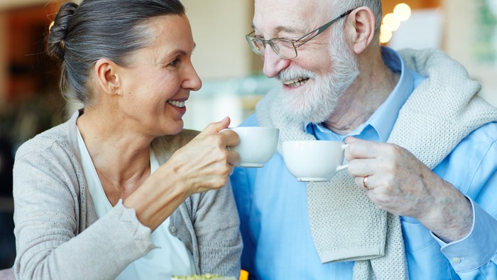 Ein älteres Paar genießt gemeinsam eine Tasse Tee und lacht.