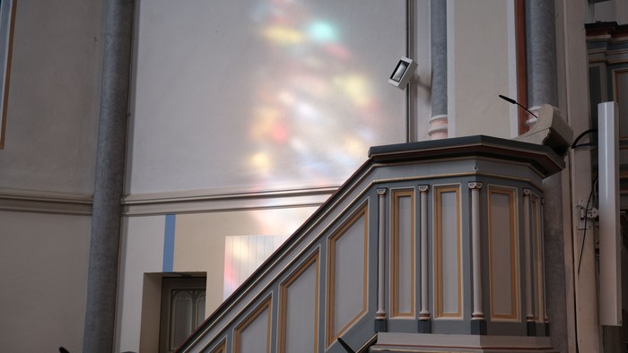 Ein Treppenhaus mit Holzgeländer und einem farbigen Lichtstrahl an der Wand