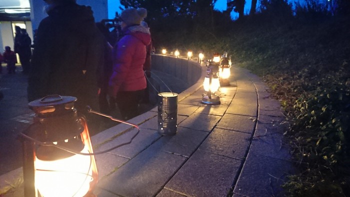En gruppe af mennesker holder lys på en sti ved natten