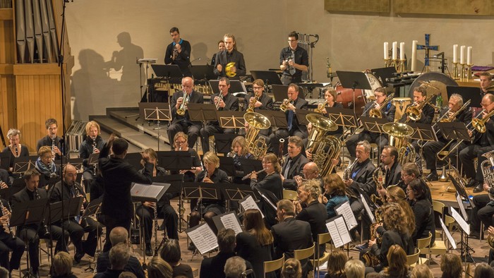 Ein Orchester spielt in einem großen Saal vor einem Publikum.