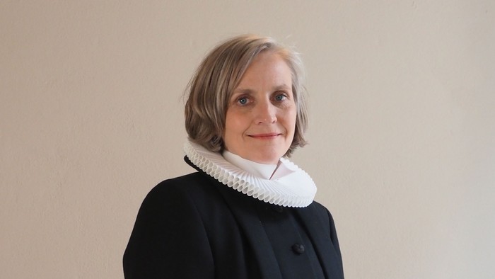 Kvinde i sort kaptajnmø, hvid krage og hvid kuffe.