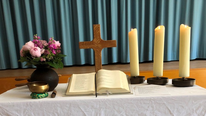 Ein Tisch mit Kreuz, Bibel, Kerzen und Blumen in einer Kirche