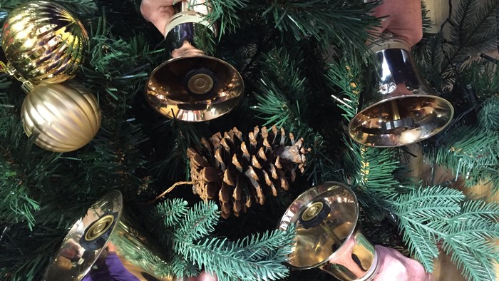 Hands placing ornaments on a Christmas tree
