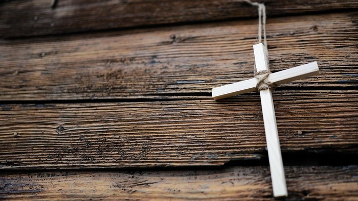 Ein kleines Holzkreuz liegt auf verwitterten Holzbohlen.