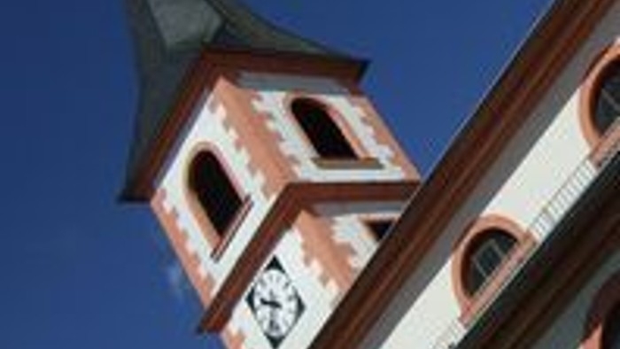 Ein charmanter Kirchturm mit Uhr und spitzem Turmhelm vor einem klaren blauen Himmel.