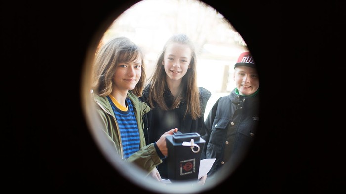 Tre unge piger poser sammen, den ene holder et kamera.