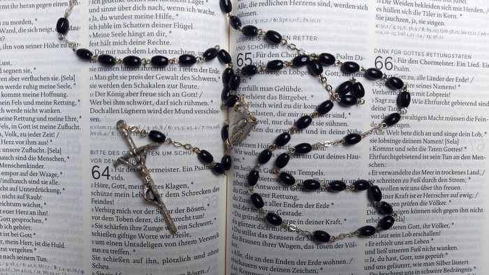 Nahaufnahme eines offenen Buches mit deutschem Text und schwarzen Flecken, die Teile der Seiten verdecken.