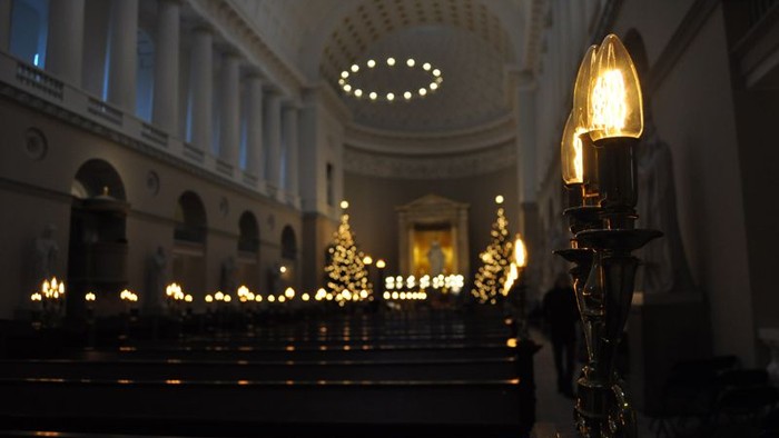 En kirkeindendørs scene med lysende lysstake og rækker med bænke.
