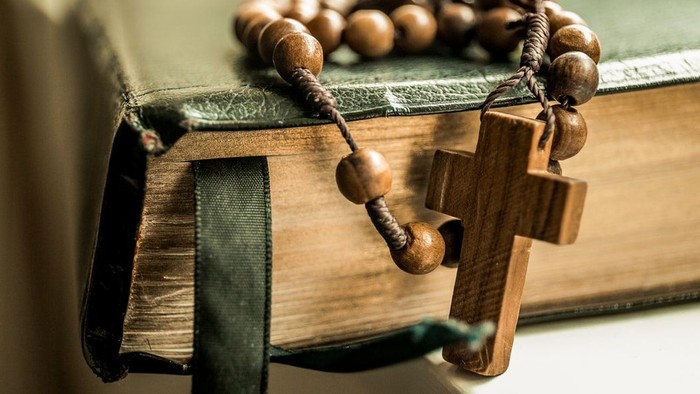 Holzkreuz und Rosenkranz auf einem Buch