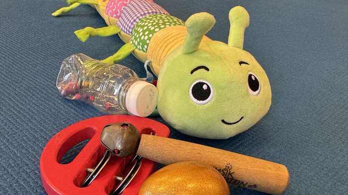 Stofftier, Schlüssel, Flasche und Holspielzeuge auf einer blauen Oberfläche.