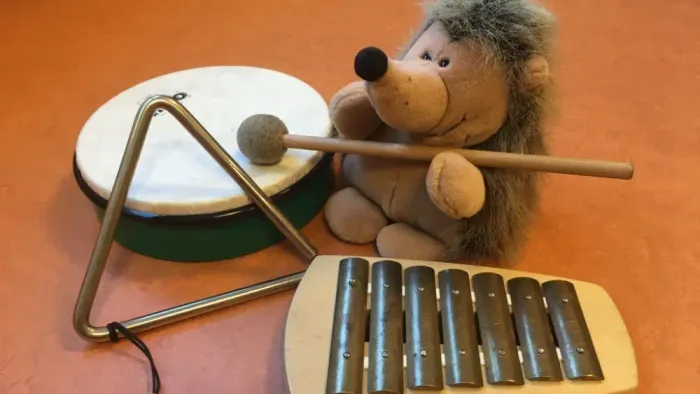 Stofftier, das Musikinstrumente spielt, darunter eine Trommel und ein Xylophon.