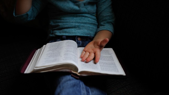 Ein Kind sitzt im Dunkeln und liest ein Buch.