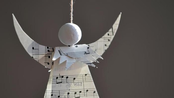 Ein Engel aus Notenpapier mit weißem Kopf und Flügeln.