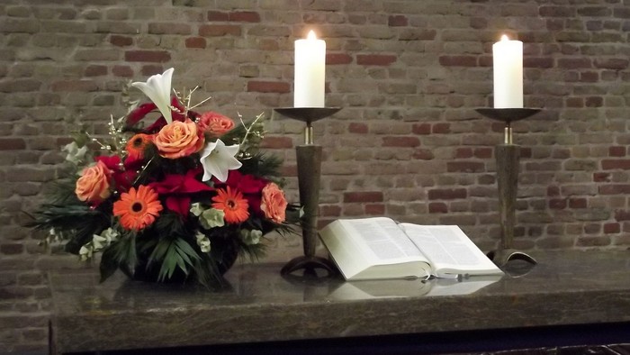 Blumenstrauß und Kerzen vor Ziegelwand