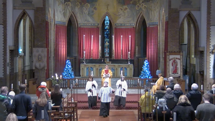 Church service with clergy and congregation, decorated with Christmas trees