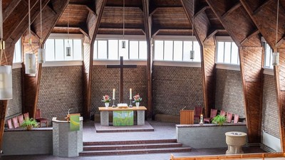 Ein moderner Wohnraum mit hohen Decken und großen Fenstern, eingerichtet mit Holz und grünen Akzenten.