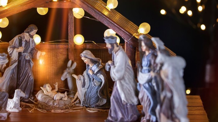 Christmas nativity scene with figures and lights.