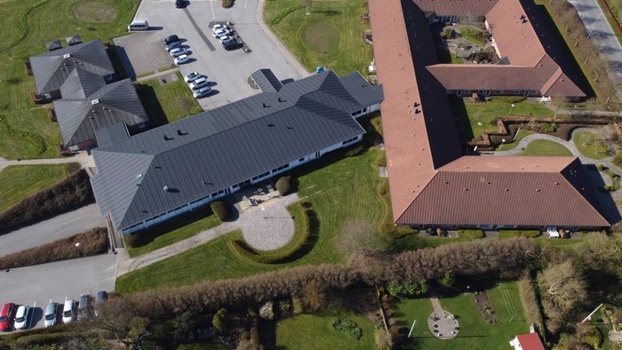 En stor bygning med fladt tag og flere parkeringseksplanter.