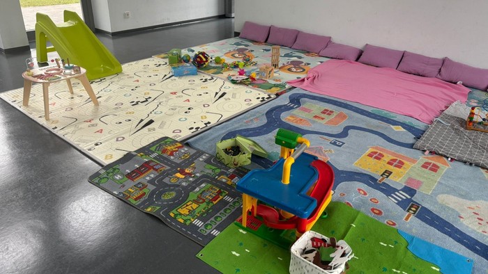 Heller Spielbereich mit thematischen Teppichen, Spielzeug und gemütlichen Sitzgelegenheiten für das fantasievolle Spielen von Kindern.