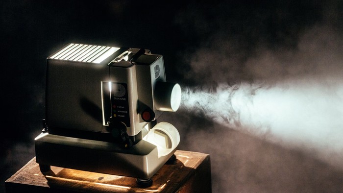 En gammel filmprojektor på en træboks med røg.