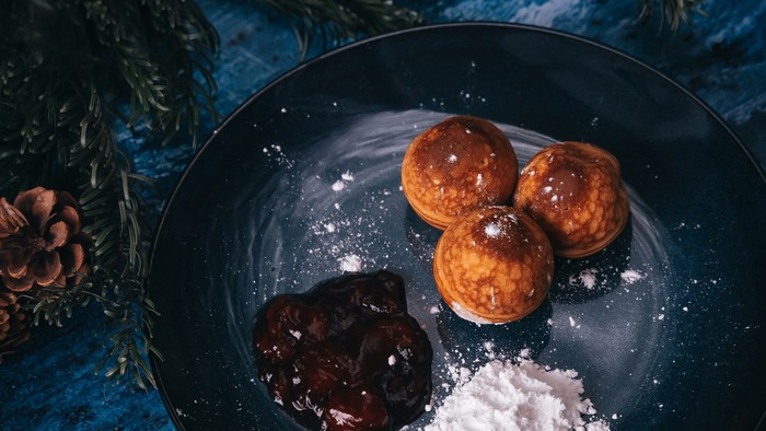 Tre donuts på en tallerken med chokoladesauce og flormelis.