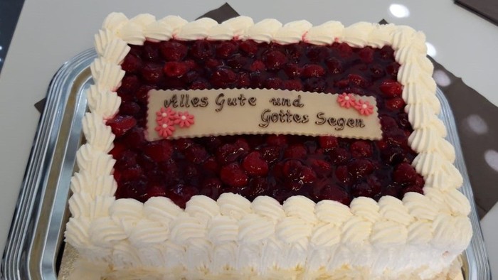 Eleganter quadratischer Kuchen mit Beerfüllung und weißer Glasur, verziert mit einer herzlichen deutschen Botschaft.