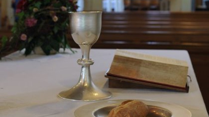 Ein Tisch in einer Kirche mit Kelch, Buch und Hostien.