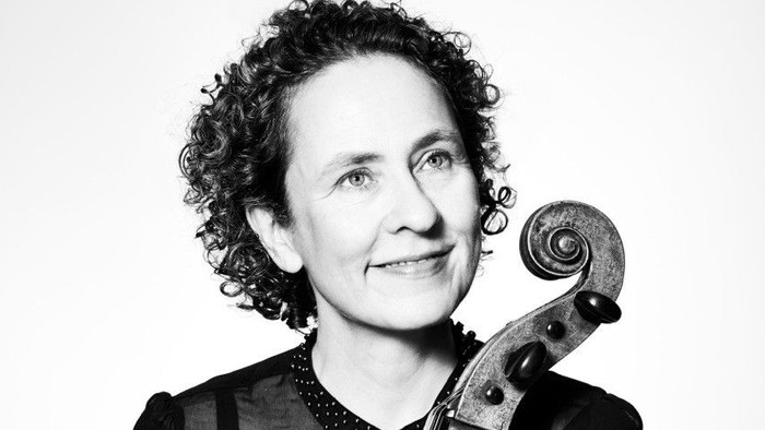 Kvinde, der holder en cello, smiler.